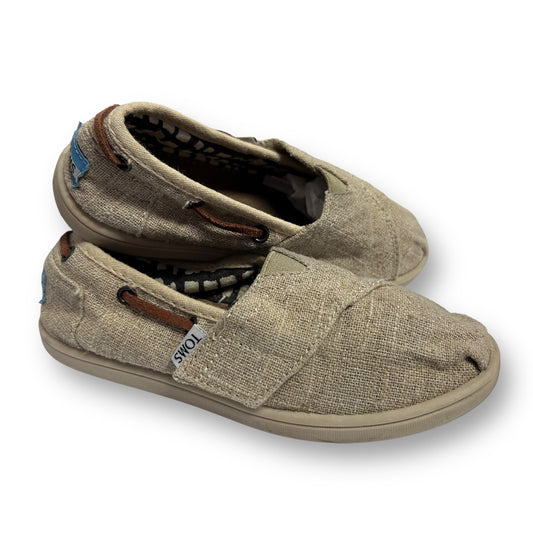 A pair of tan Toms Big Boy size 11 canvas easy-on shoes with lace-up closure and a flat sole.