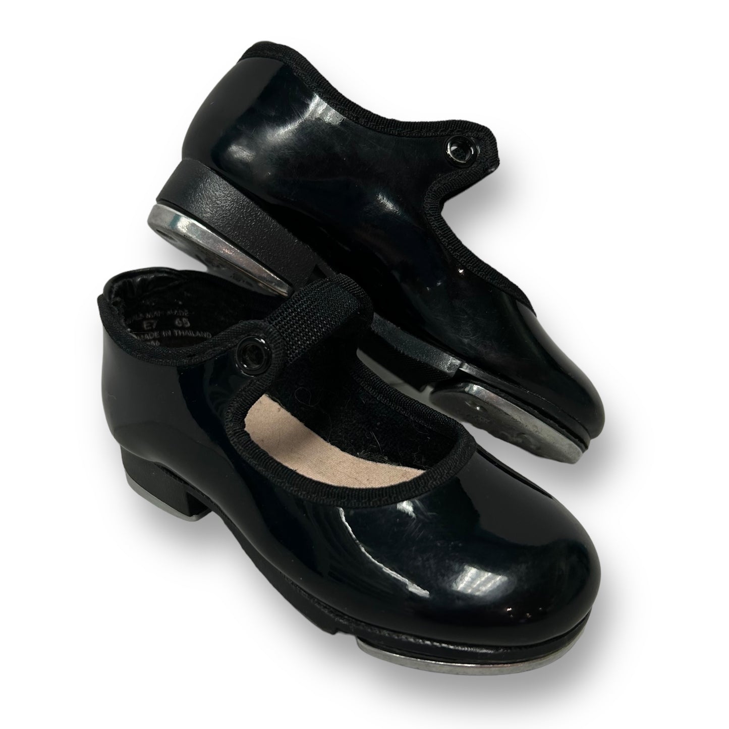 A pair of black patent leather tap shoes for toddlers, featuring a shiny finish and designed for dance.