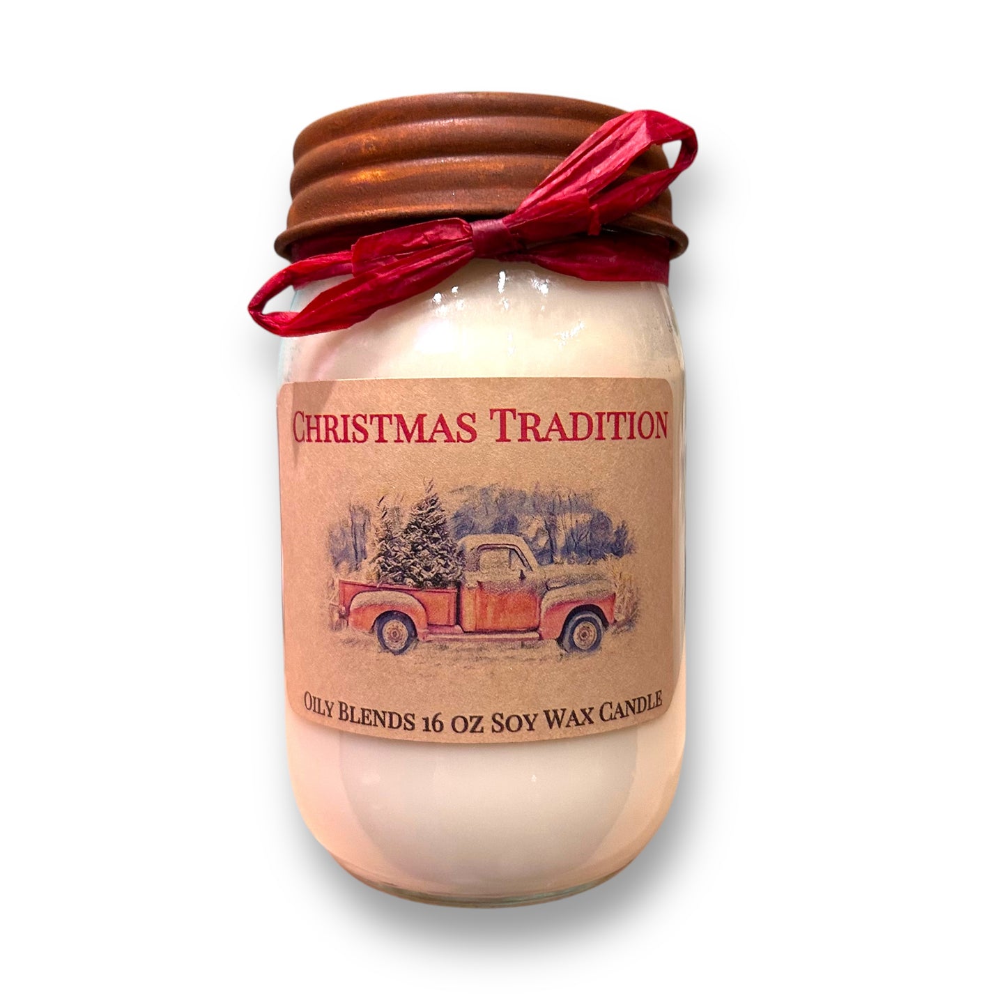 A soy wax candle in a glass jar with a red decorative bow on top, labeled 'Christmas Tradition' and indicating it's a 16 oz wax candle.