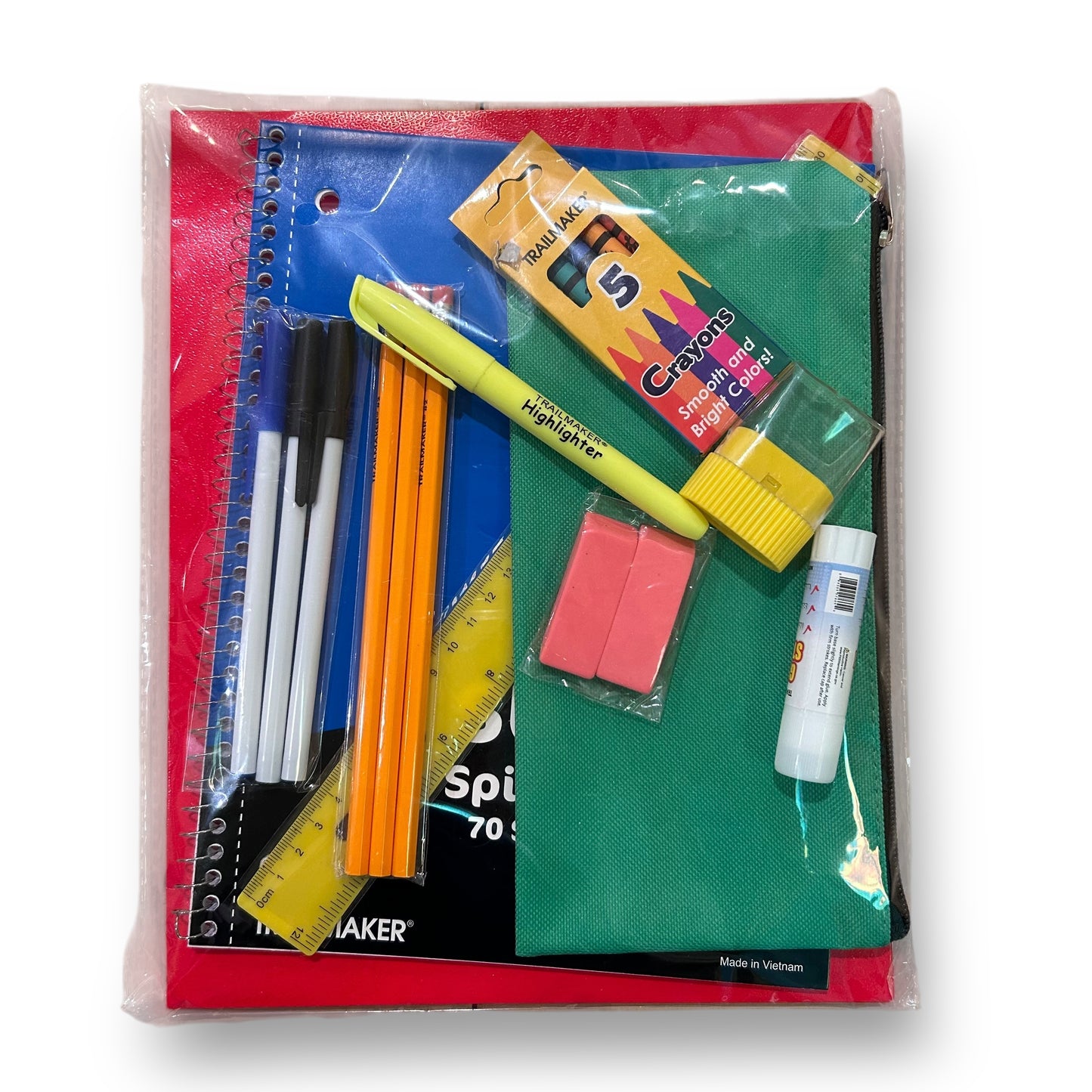 A collection of school supplies including pens, paper, a notebook, a ruler, and other office items packaged in a clear plastic bag.