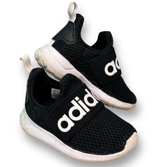 A pair of black Adidas slide-on athletic sneakers for toddlers with white branding on the side.