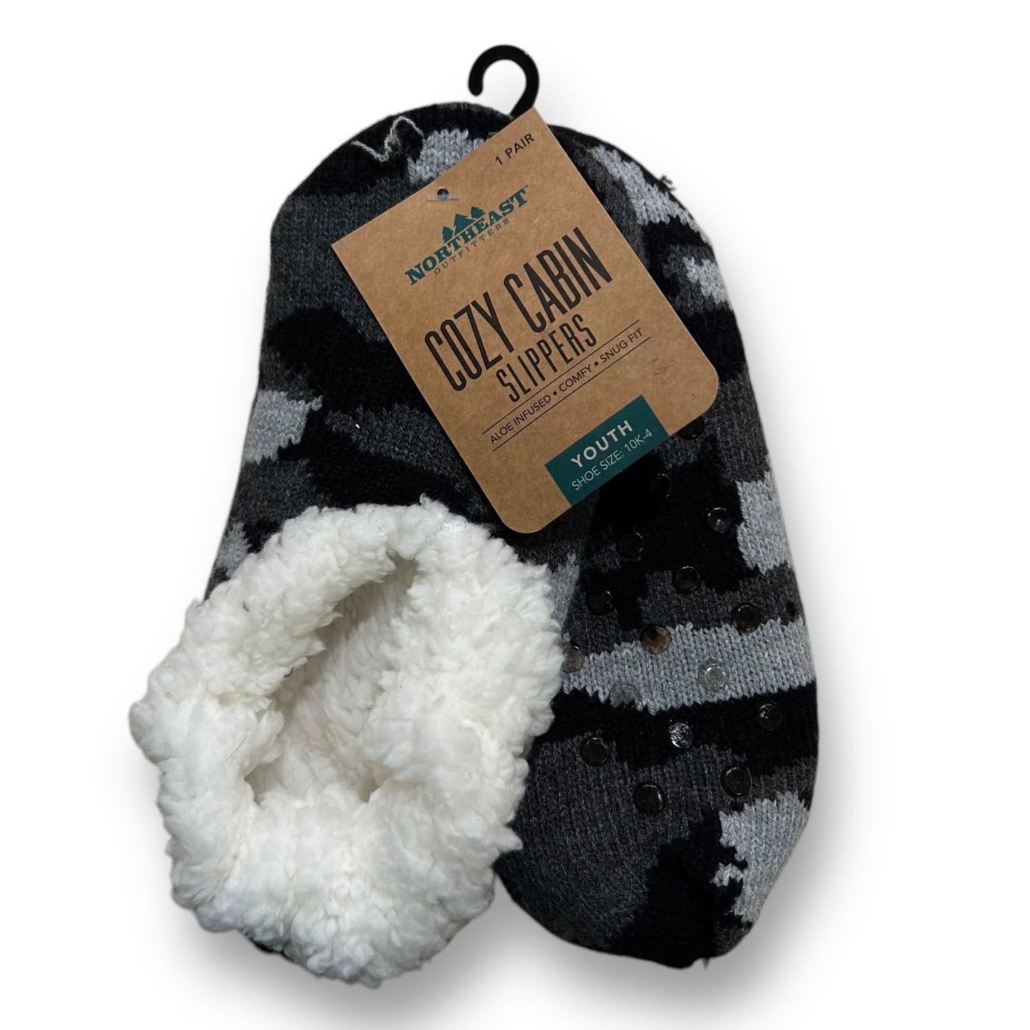 Youth size camouflage cabin slippers with white faux fur lining, displayed on a hanger with a brand tag showing.