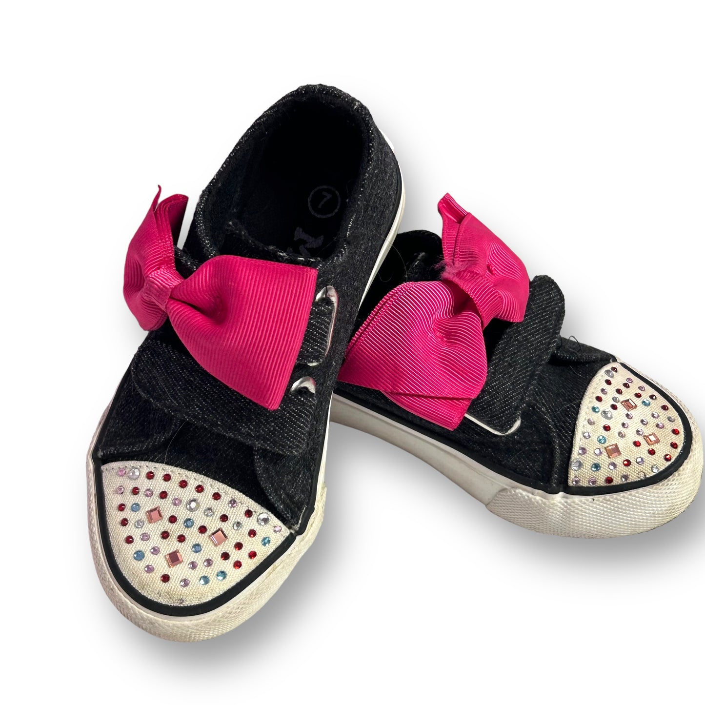 A pair of dark blue denim-style toddler girl sneakers with a pink bow on the toe and a decorative diamond pattern on the sole.