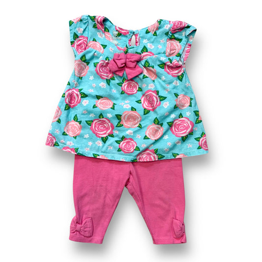 A baby girl's outfit featuring a short sleeve floral print top in pink and aqua colors, and pink pants.