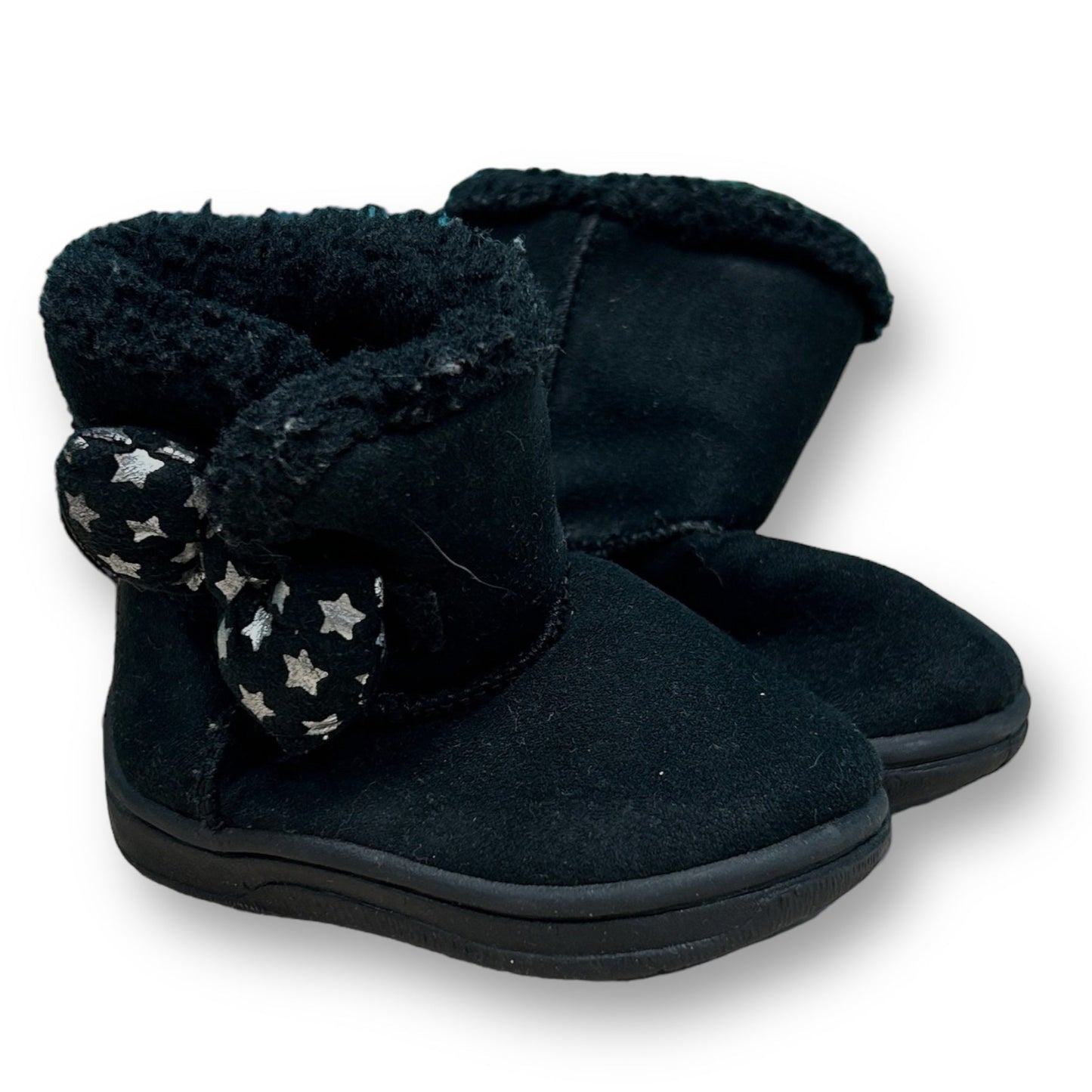 A pair of black suede baby girl boots with a bow and stars pattern on the top, a Velcro closure, and a solid black color.
