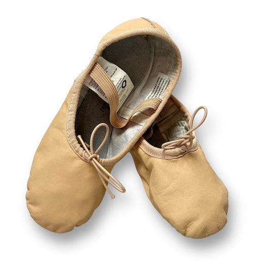 A pair of pink ballet shoes for girls, with the brand Revolution visible on the strap.