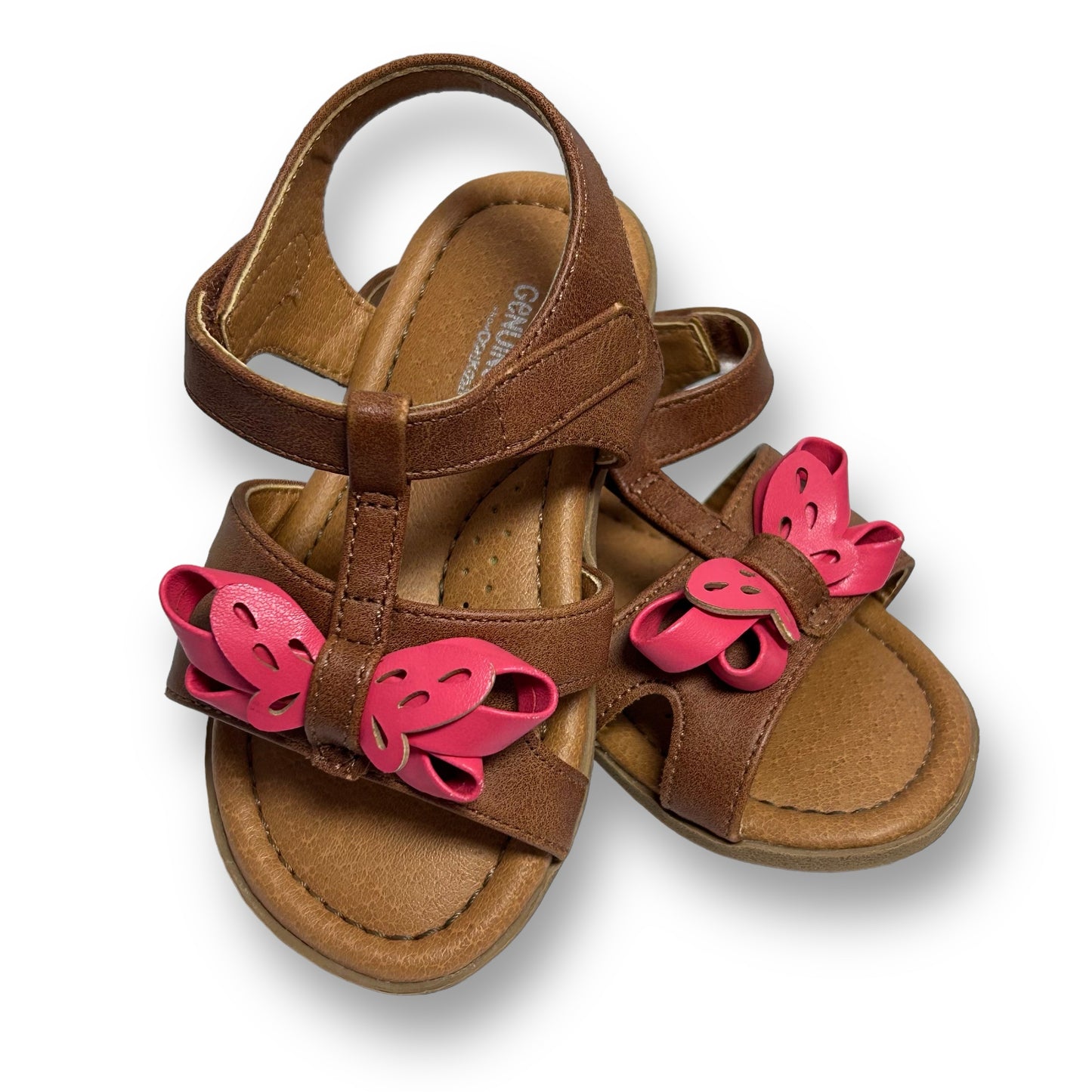 A pair of brown leather-like toddler girl sandals with pink bows on the straps.