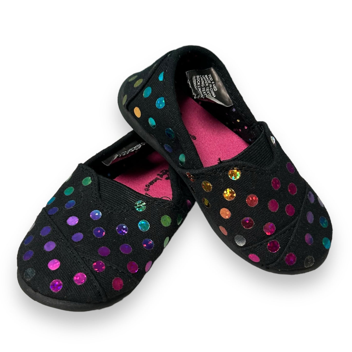 A pair of black toddler girl slide-on shoes with multicolored shimmery designs on the top.