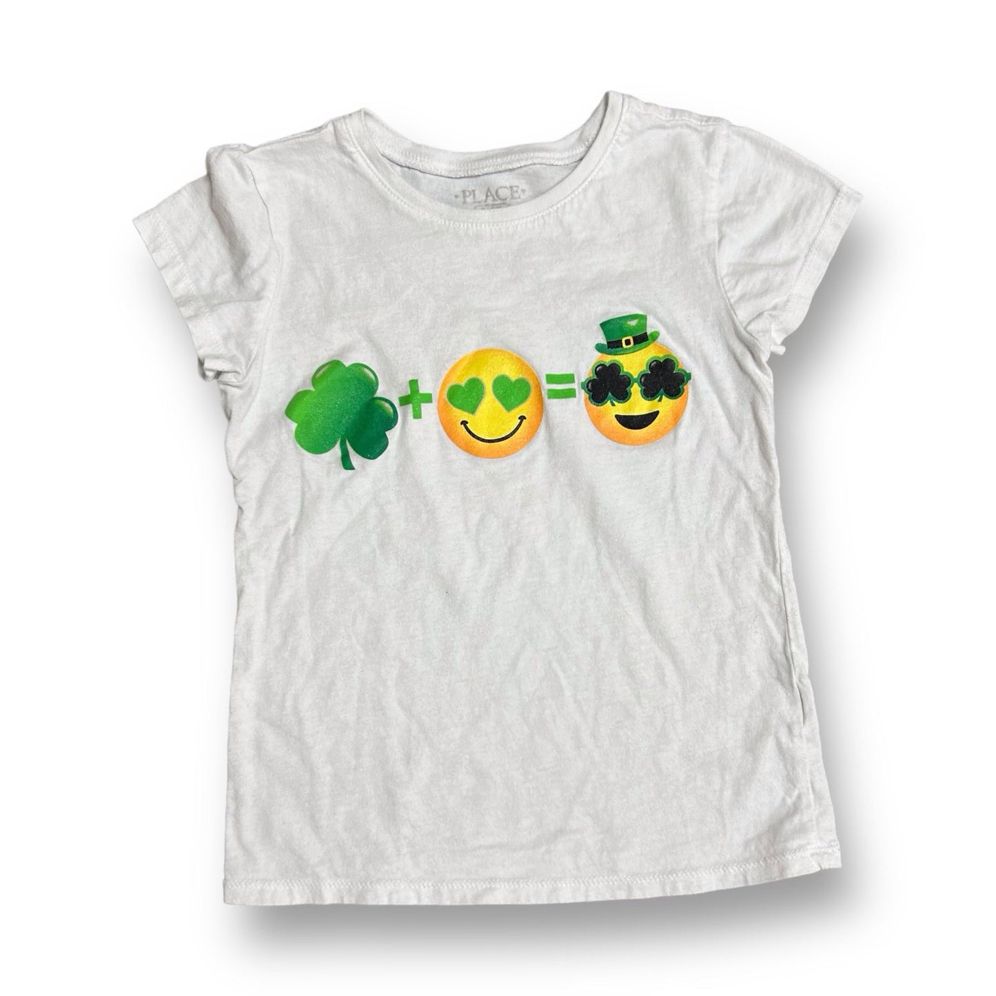 A white short-sleeved Children's Place t-shirt featuring a St. Patrick's Day themed emoji design with a green shamrock, black sunglasses, and a smiling face graphic.