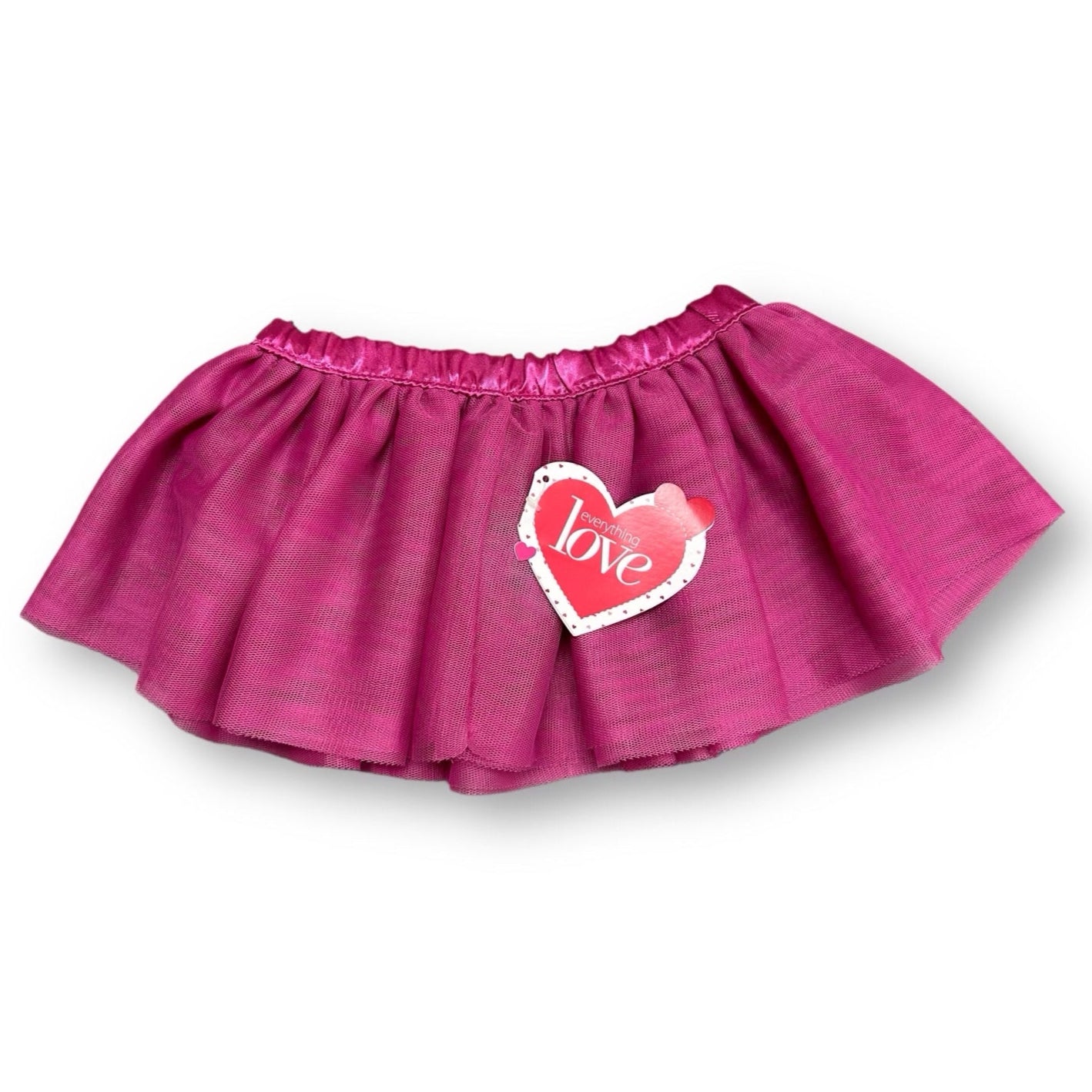 A pink tulle skirt for girls, with a scalloped edge and a heart-shaped patch on the side that says 'love'.