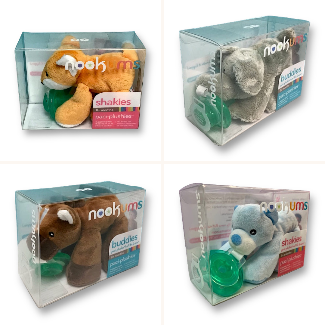 Four packaged Nookums Paci-Plushies Buddies plush pacifier clips in various animal designs, including a fox, bear, horse, and elephant, displayed in transparent plastic boxes.