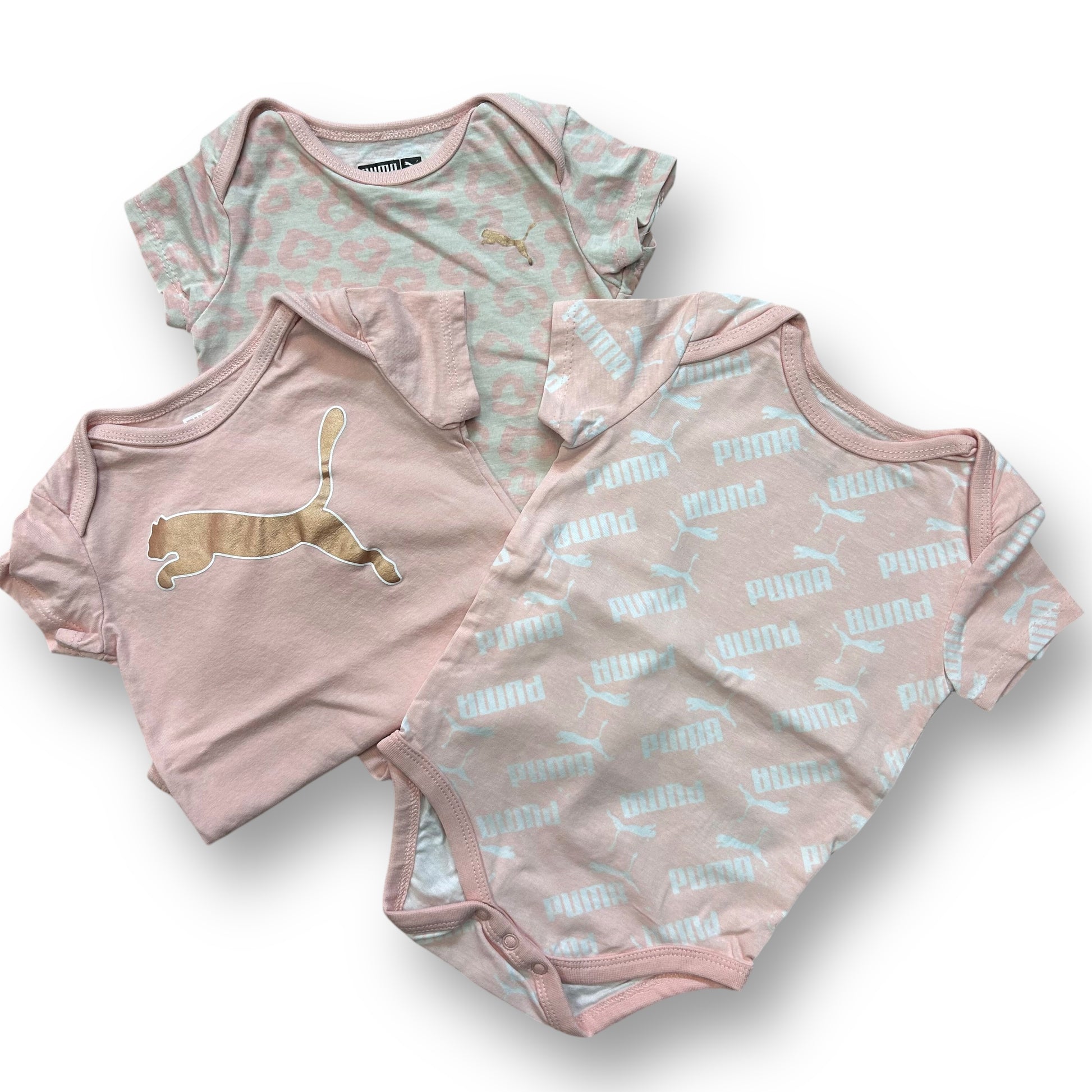 A set of three pink and white short sleeve snap bottom bodysuits for girls, each featuring a different design with a cat and the Puma logo.