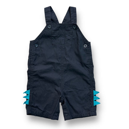 A pair of dark gray baby overalls with dino accents on the legs, featuring a one-piece design.