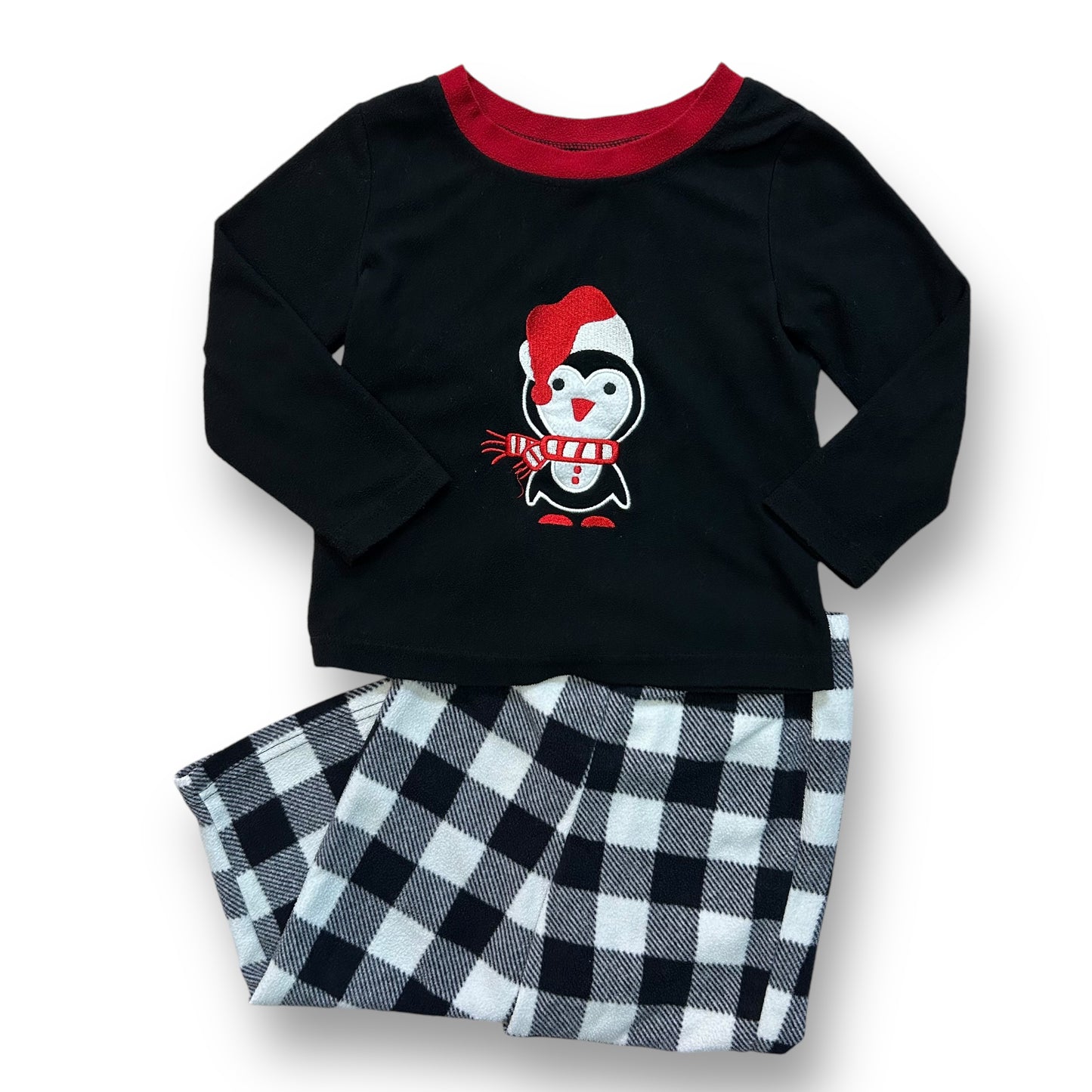 A black fleece pajama top with a white and red checkered pattern and a character design on the front, and black fleece pants with a checkered pattern.