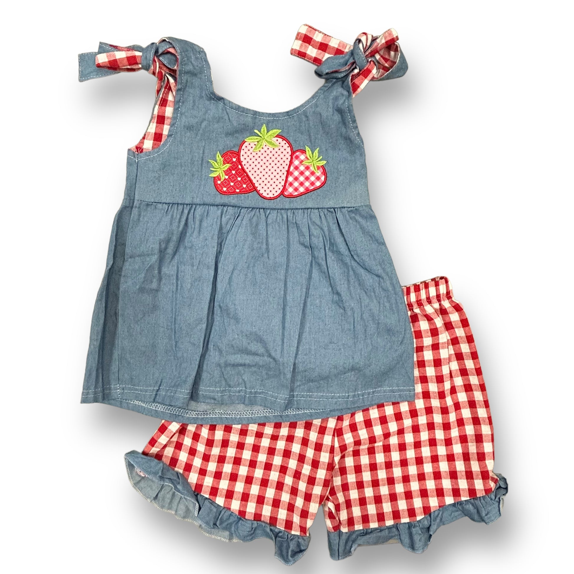 A girls' boutique outfit set consisting of a blue denim dress with a strawberry and checkered pattern on the front and red checkered shorts.