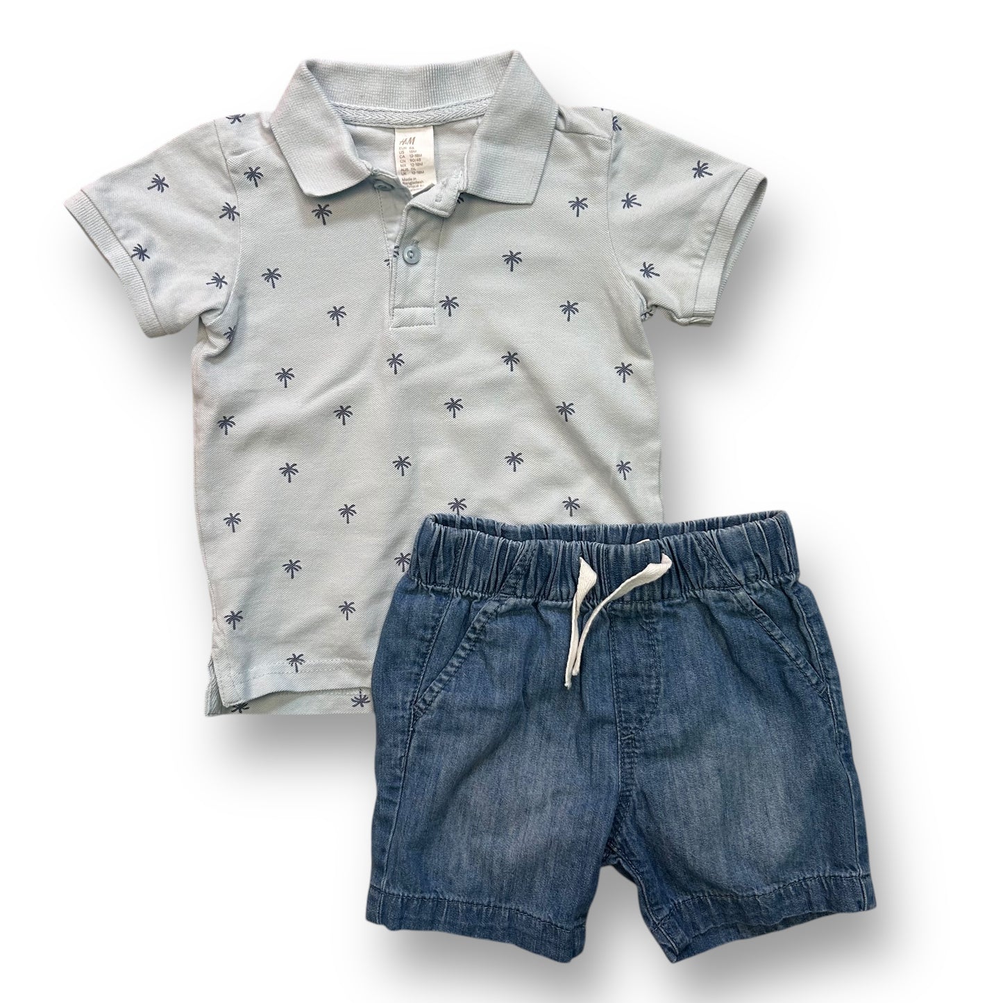 A baby blue polo shirt with a collar and short sleeves, and denim shorts, both with a button-up closure. The polo shirt has a tropical pattern and the denim shorts are plain.