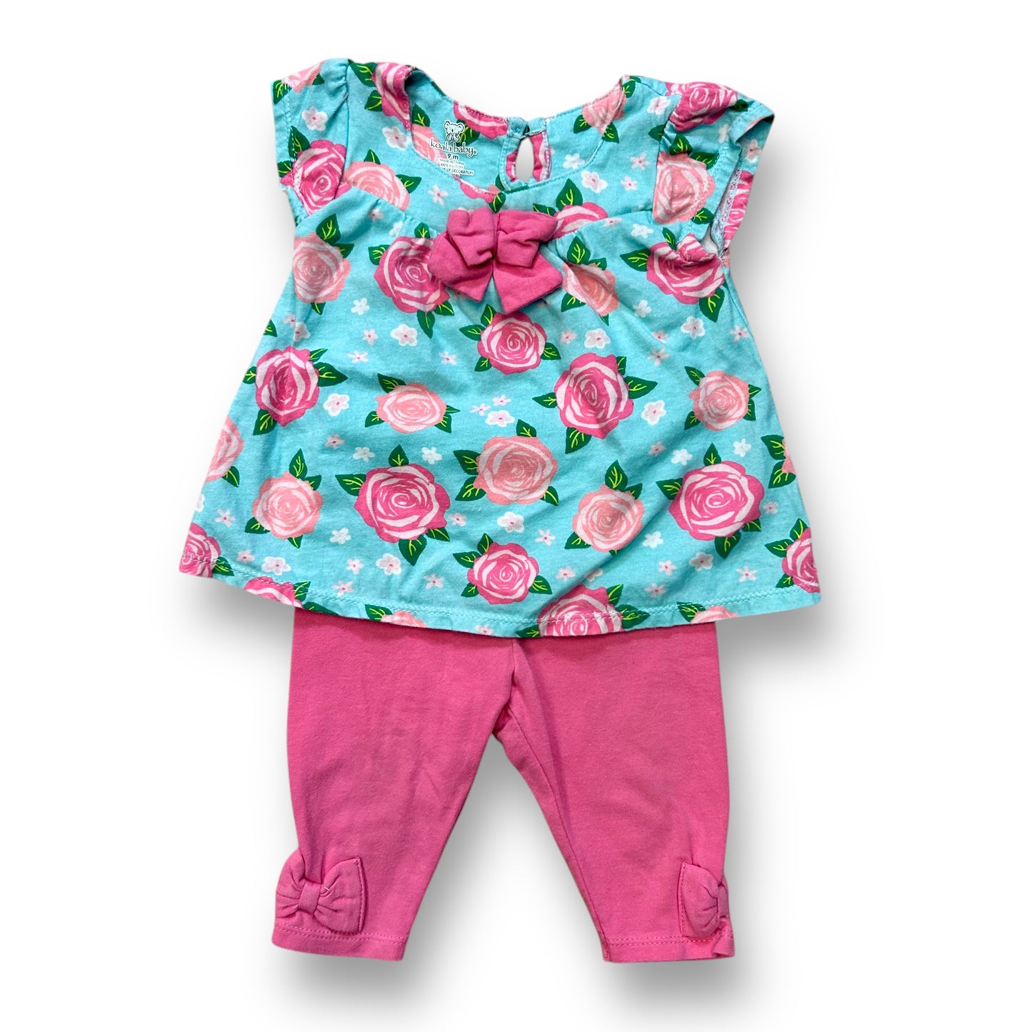 A baby girl's outfit featuring a short sleeve floral print top in pink and aqua colors, and pink pants.
