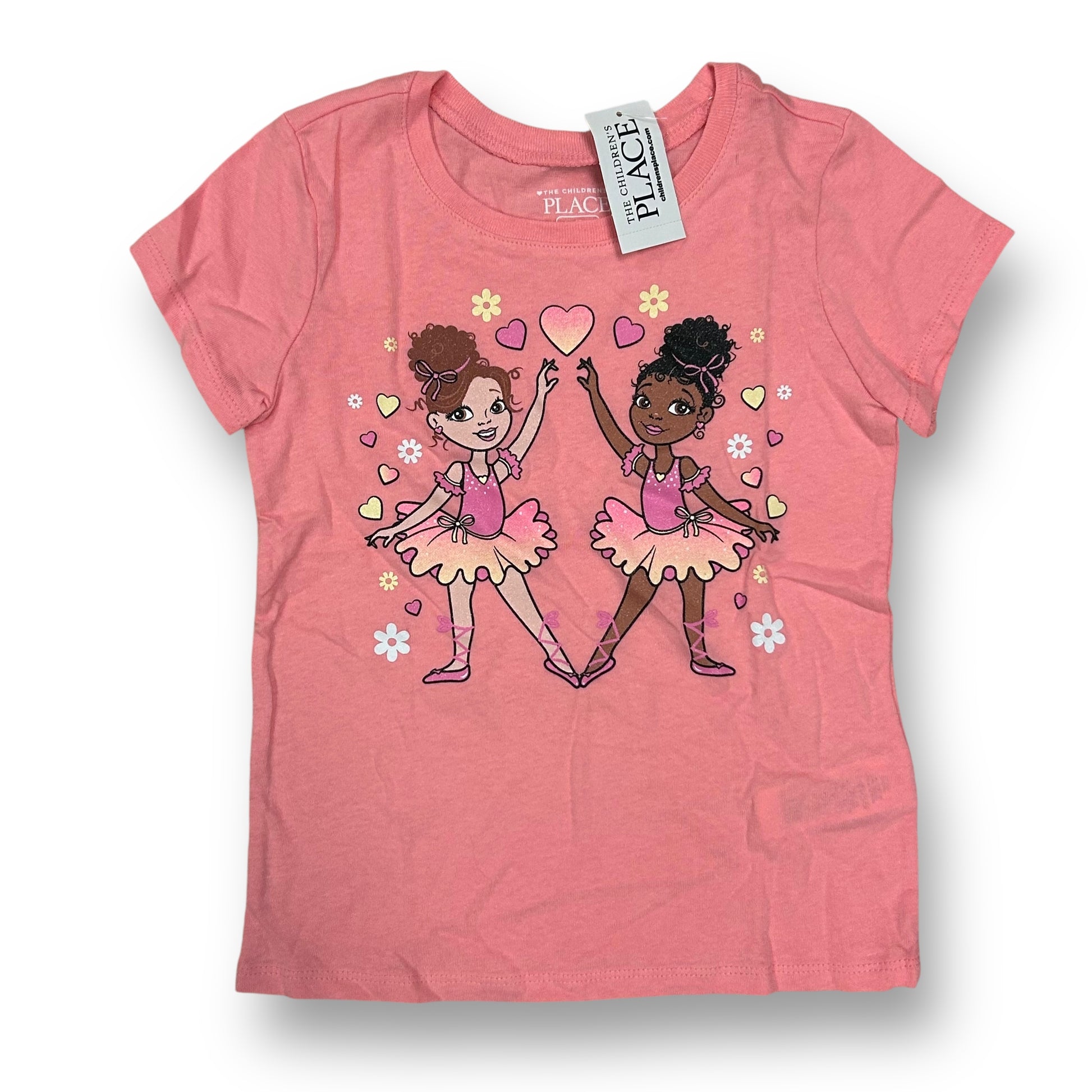 A pink short-sleeve shirt featuring an illustration of two cartoon girls in pink ballet outfits, with hearts and flowers around them.