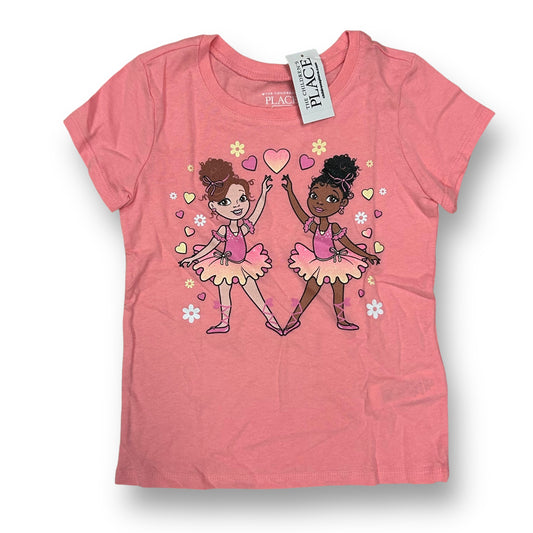 A pink short-sleeve shirt featuring an illustration of two cartoon girls in pink ballet outfits, with hearts and flowers around them.