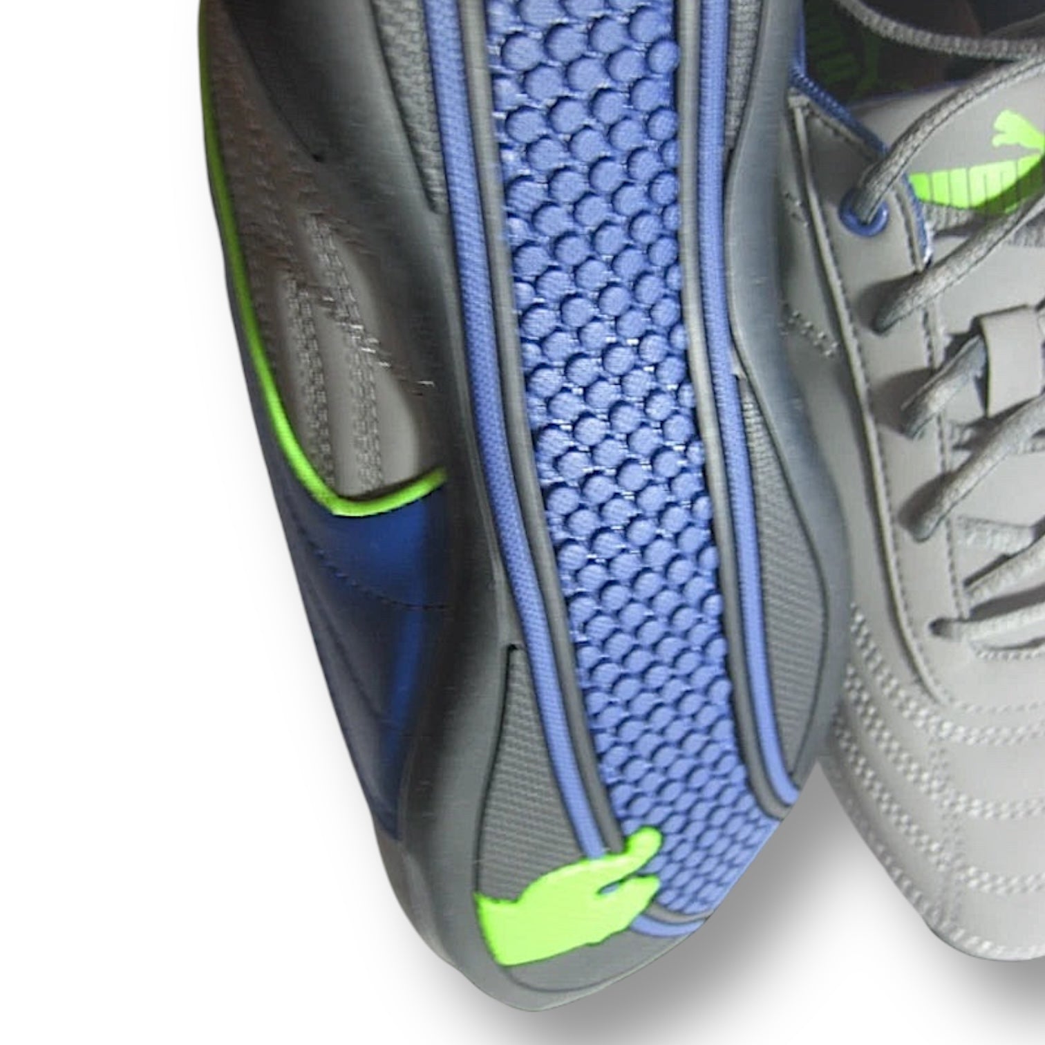 Close-up of a gray and blue athletic shoe with green accents on a white background