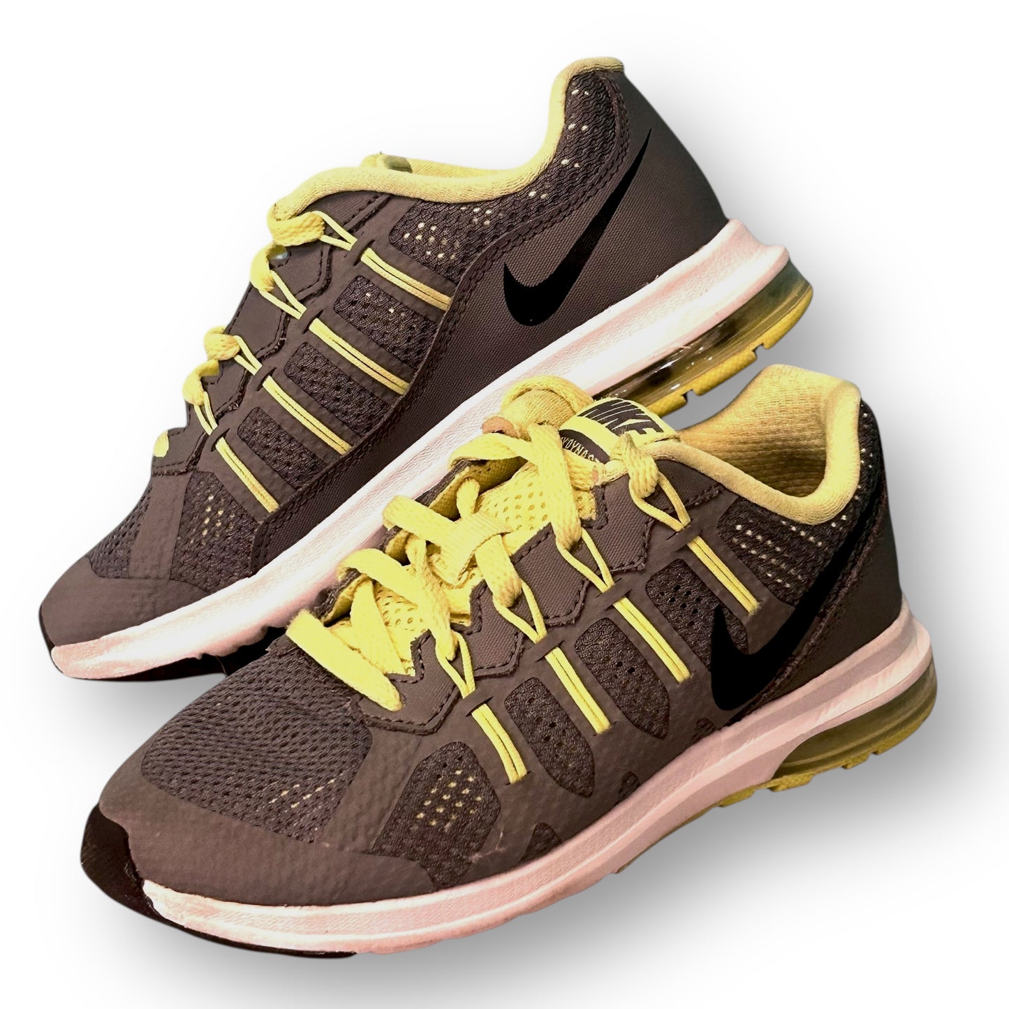 Gray Nike running shoes with yellow laces on a white background