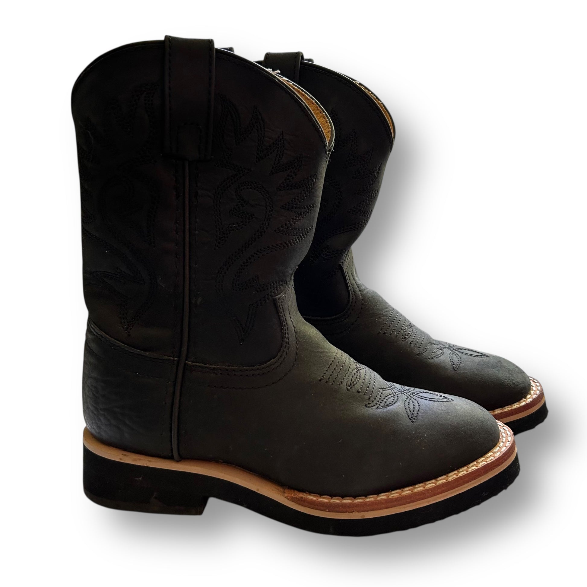 Pair of Justin black leather cowboy western boots with brown soles on a white background