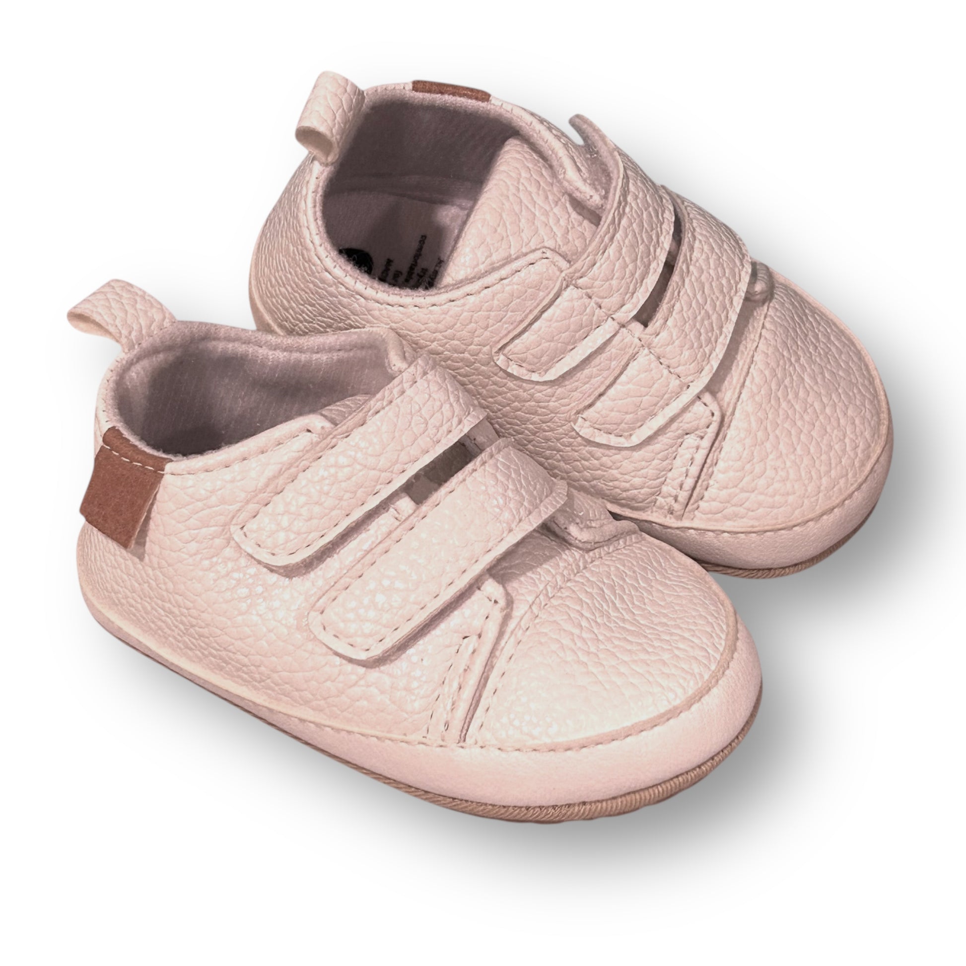 Pair of white baby shoes with velcro straps on a white background
