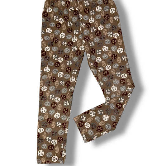 Brown pants with a pattern of peace signs and skulls on a white background